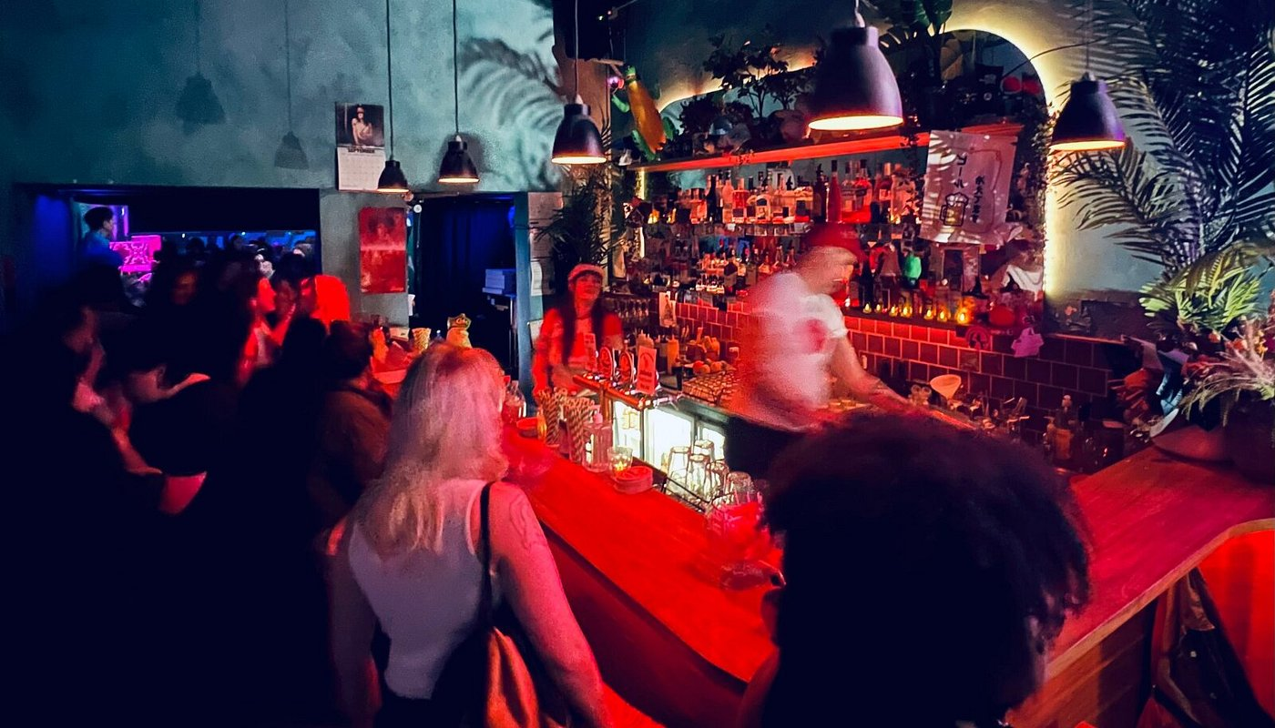 Guests and bartenders at Sugar Glider’s front bar under red and blue lighting